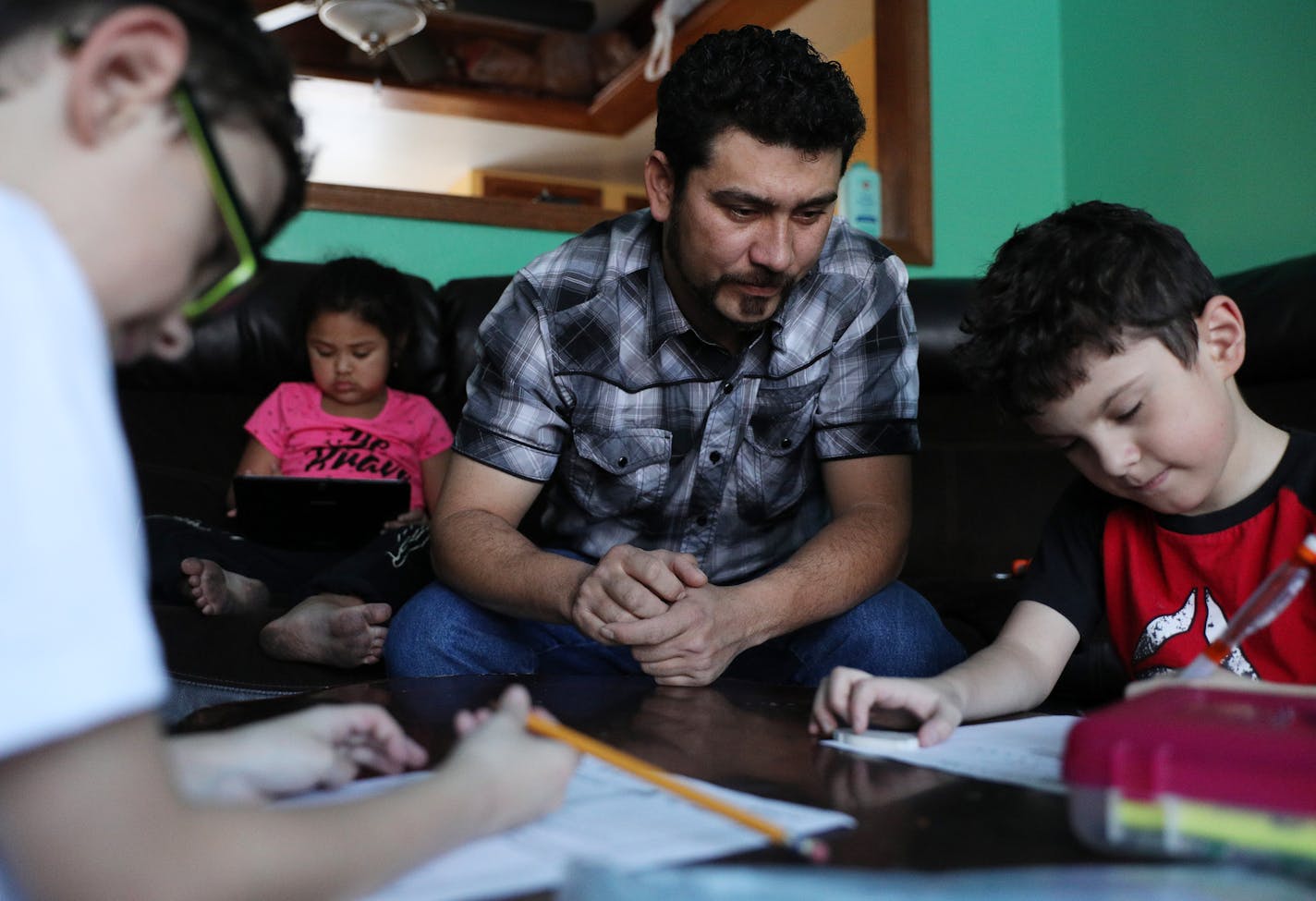 Santiago Portillo's helped his twins Luis Eduardo, left, and Luis Vicente, 8, with their homework as his niece Angela, 5, sat nearby. ] ANTHONY SOUFFLE &#xef; anthony.souffle@startribune.com Santiago Portillo's helped his children with their homework after school Friday, Jan. 12, 2017 in Maplewood, Minn. Portillo's employer, an erosion control company, is sponsoring him for an employment-based green card. He now relies on a program called Temporary Protected Status for citizens of El Salvador, w