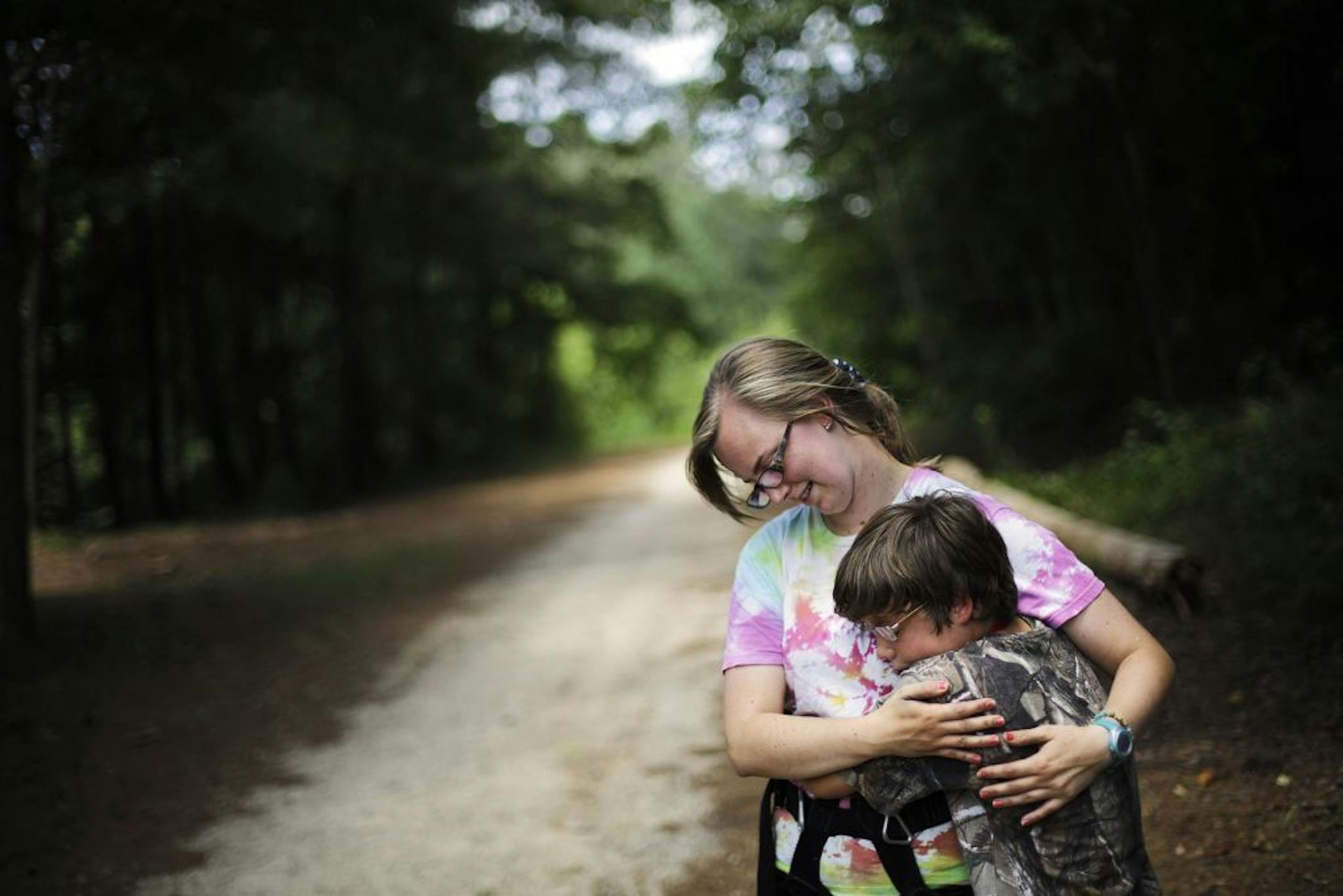 In this July 15, 2014 photo, Liam Harrison, 13, of Nashville, Tenn., right, embraces camp worker Katie Lesesne, 21, while experiencing a tic where he feels the urge to hug someone in proximity at Camp Twitch and Shout, a camp for children with Tourette Syndrome in Winder, Ga. "When I get the feeling, I just want to squeeze someone," explains Harrison. "When I let go it makes me happy. It feels so awesome like I'm gaining something. It makes me feel a lot better."