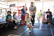Ayla Hill, 5, lunged forward while tethered to Ludy Webster with a resistance band during the children’s boxing class at Ludy’s Boxing Gym in Minn