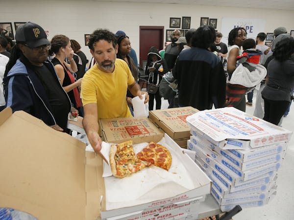 Angel Poventud, who voted early, volunteers his time to hand out pizza and snacks to people waiting in line. The wait time to vote at the Pittman Park