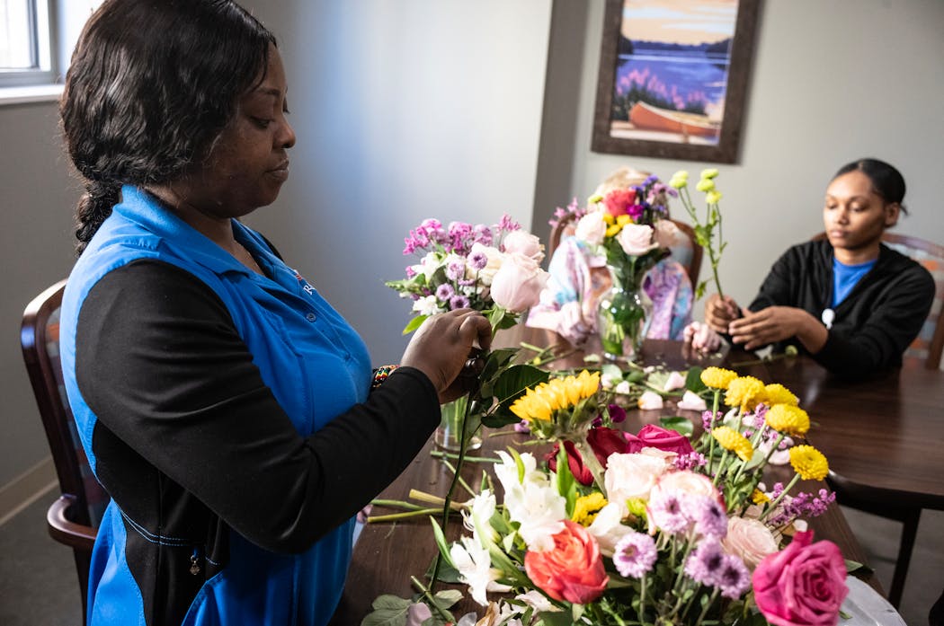 Patience Kettor left, and DéShanea Ford, employees at Aurora on France senior living, help a memory care resident arrange flowers Wednesday in Edina.