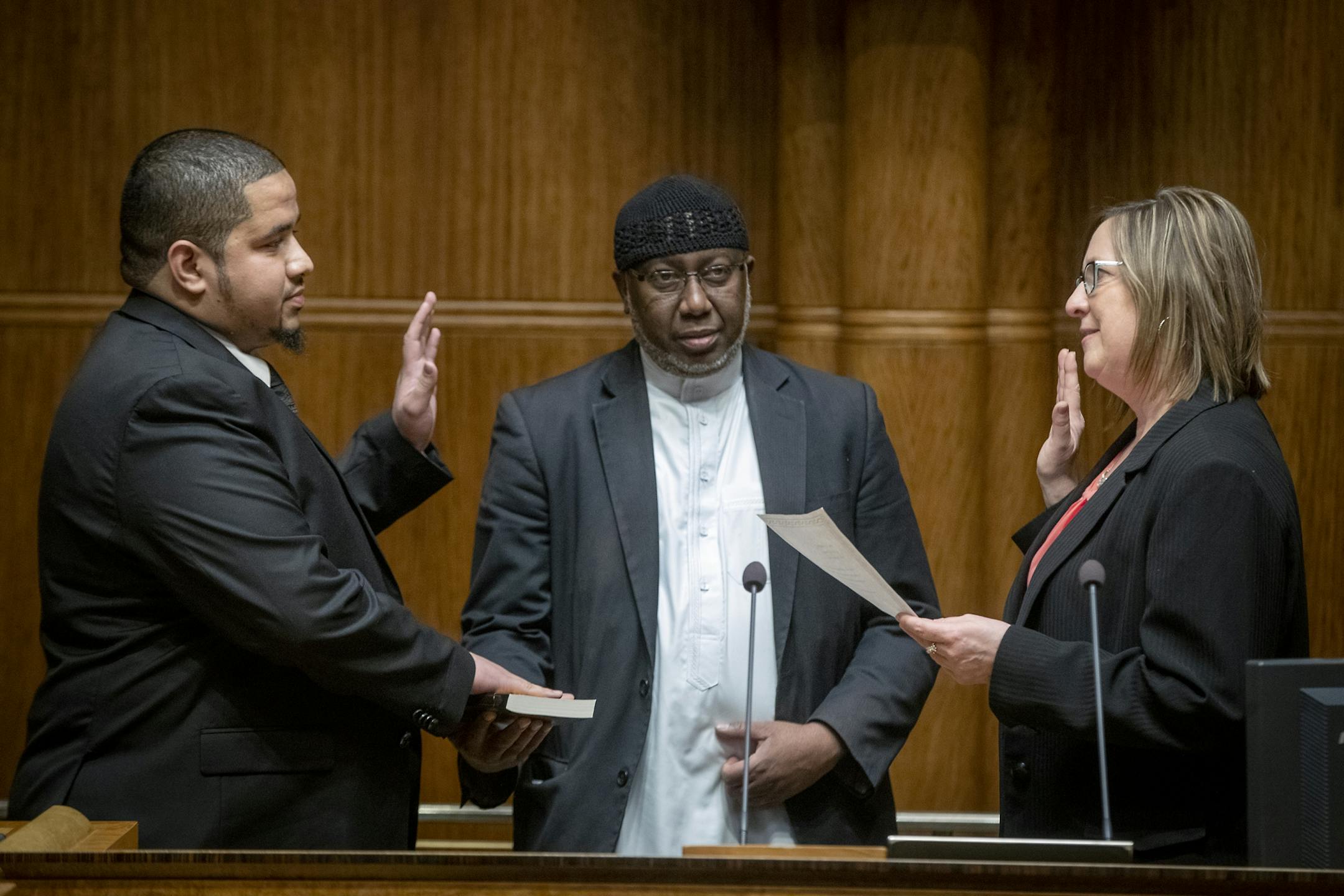 City Council Member Kassim Busuri, left, was sworn in by City Clerk Shari Moore as he placed his hand on a Qu'ran held by Imam Hassan Mohamud, at St. Paul City Hall, Wednesday, February 6, 2019 in St. Paul, MN. Busuri, a local educator, is the first Somali-American to serve on the St. Paul City Council.