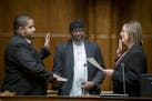 City Council Member Kassim Busuri, left, was sworn in by City Clerk Shari Moore as he placed his hand on a Qu'ran held by Imam Hassan Mohamud, at St. 