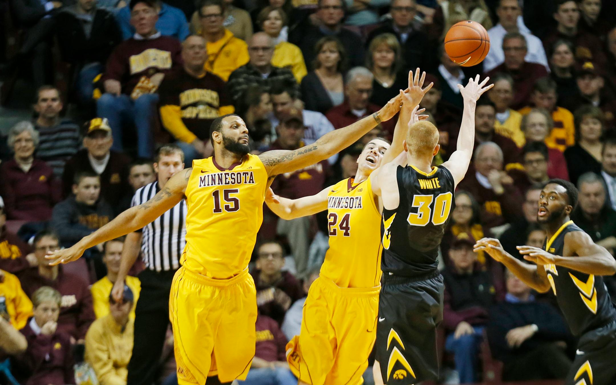 Hawkeyes forward Aaron White (30) passed the ball around Gophers center Mo Walker, left, and Joey King.