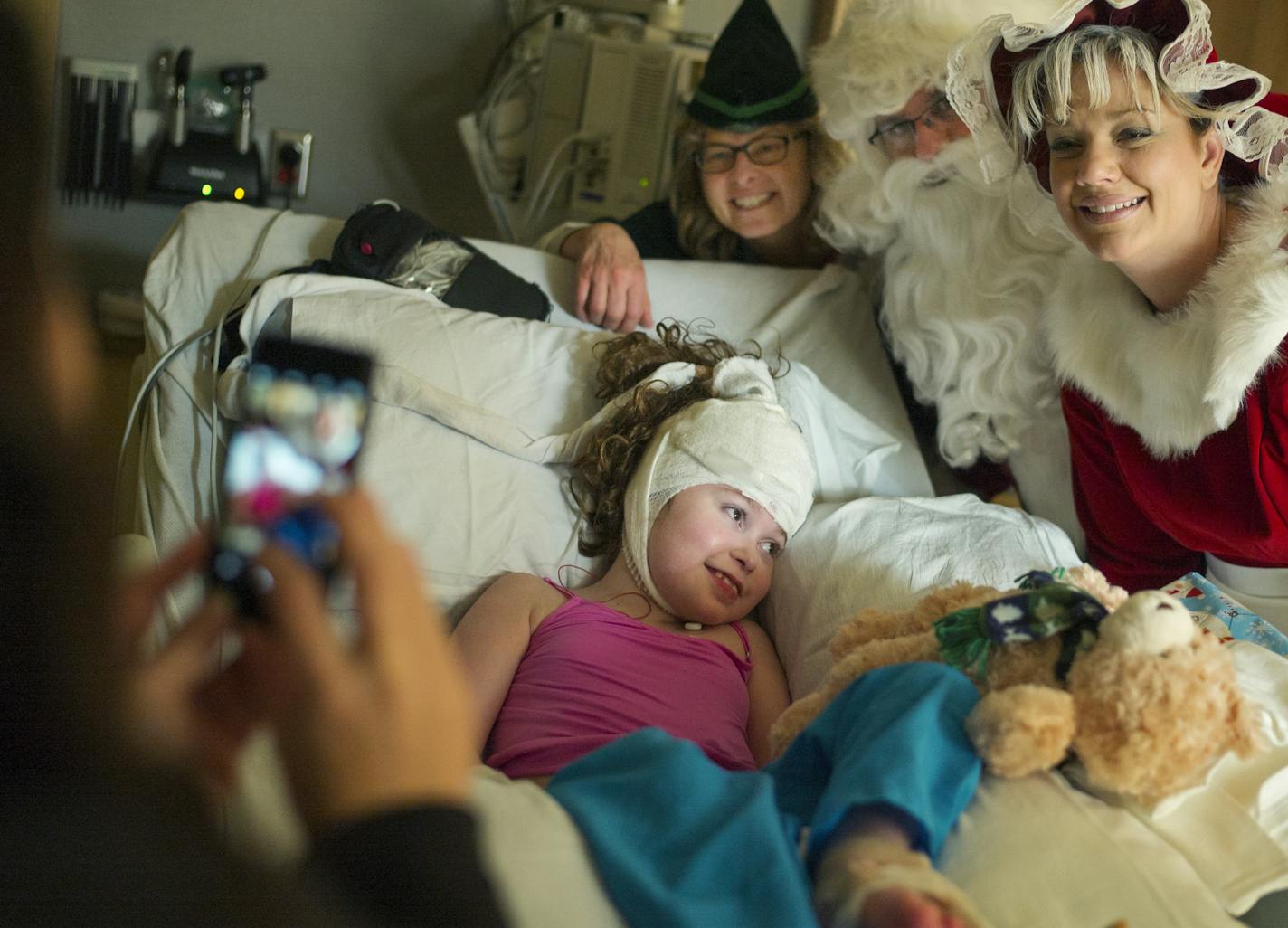 At Gillette Children's Specialty Healthcare, Sgt. Santa Claus a.k.a. Todd Feroni, his elf helper officer Lucia Wroblewski, and Mrs. Claus a.k.a. officer Amy Rahlf visited Emily Kargel, 9.5, who just underwent a treatment for epilepsy. Mom Kristy took a picture.] Richard Tsong-Taatarii/rtsong-taatarii@startribune.com