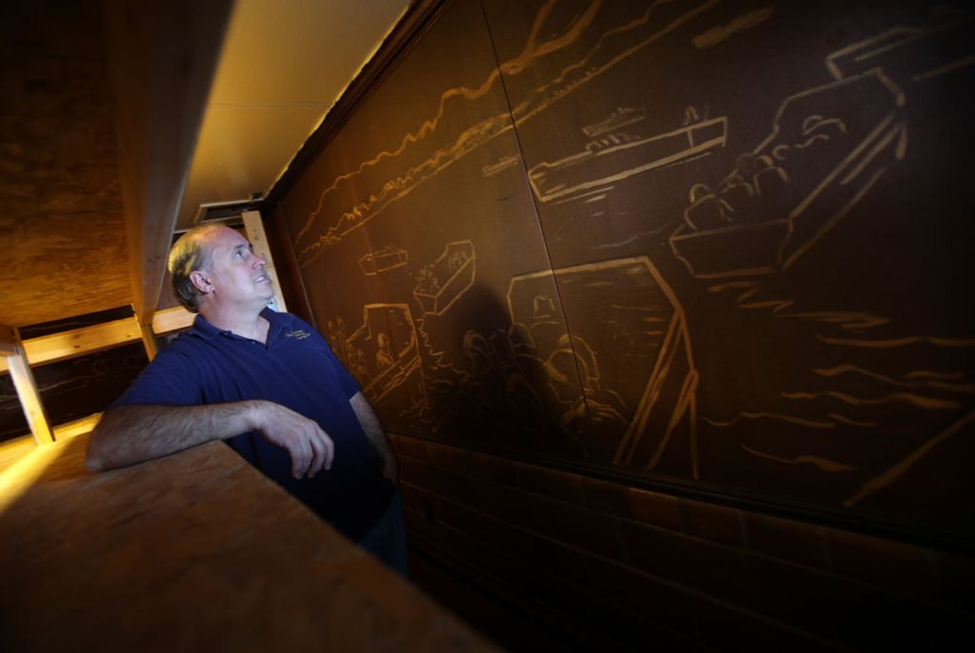 Brent Banchy stood next to a WWII mural of D-Day painted by Jo Rollins he discovered behind a shelf while cleaning the basement of the American Legion in Stillwater, Minn. He was photographed Monday, October 10, 2011.