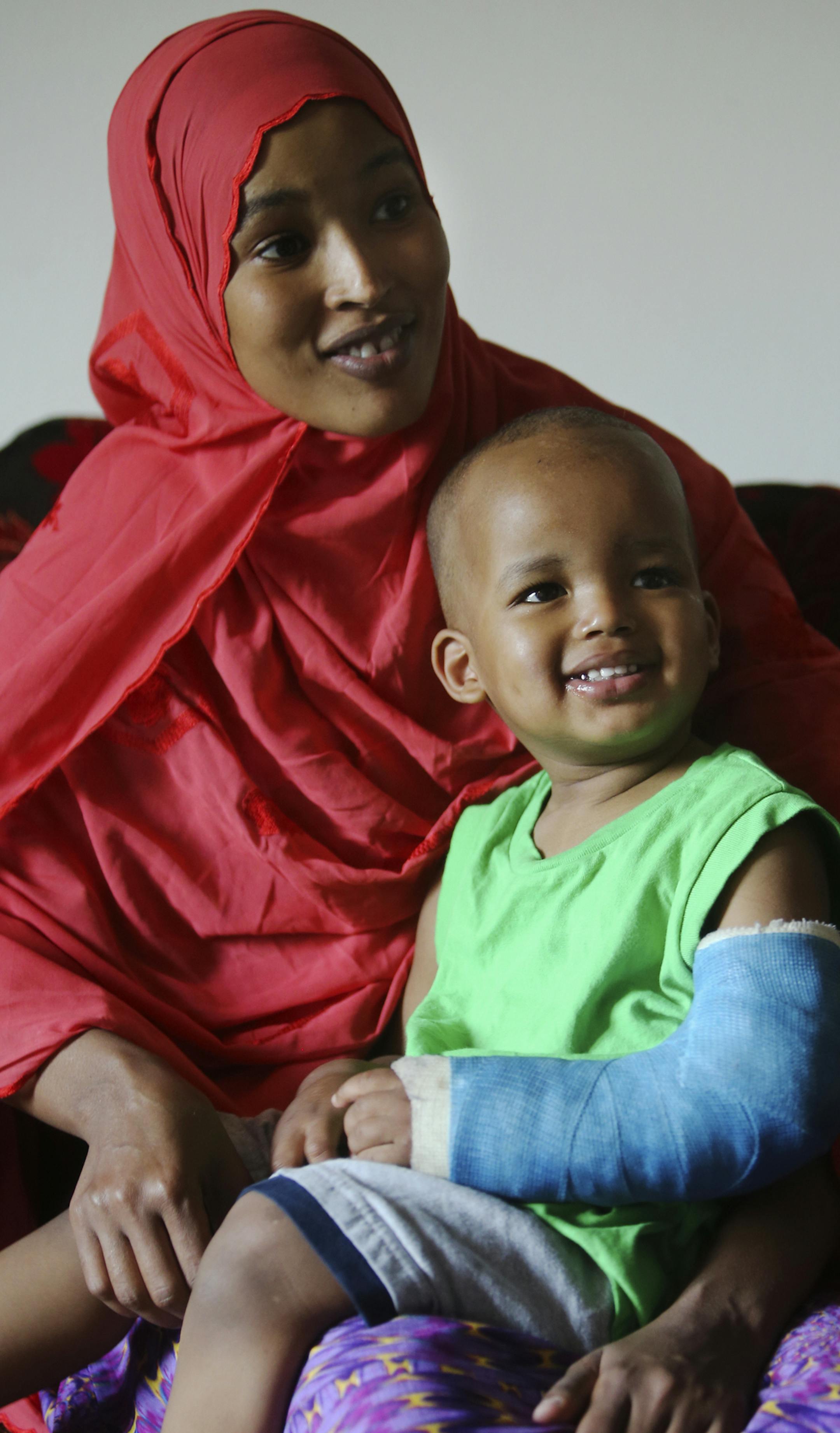 Fadumo Abudllahi holds her son Musa, 16, months, a month after Musa fell 11 stories from the family's Cedar-Riverside apartment. They were seen in their home Wednesday, June 11, 2014, in Minneapolis, MN.] (DAVIDJOLES/STARTRIBUNE) djoles@startribune.com One month ago Musa Dayib fell 11 stories from his family's Cedar-Riverside apartment, and not only lived, but is out of the hospital and moving about like a typical 16 month-old child.