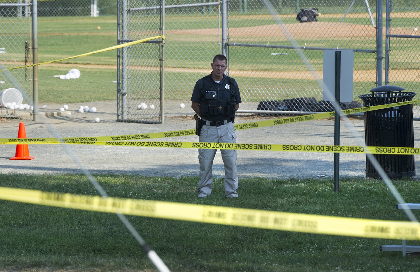 A police office stands watch behind police tape near strewn baseballs on a field in Alexandria, Va., Wednesday, June 14, 2017, after a multiple shooting involving House Majority Whip Steve Scalise of La. (AP Photo/Cliff Owen) ORG XMIT: MIN2017061415342100