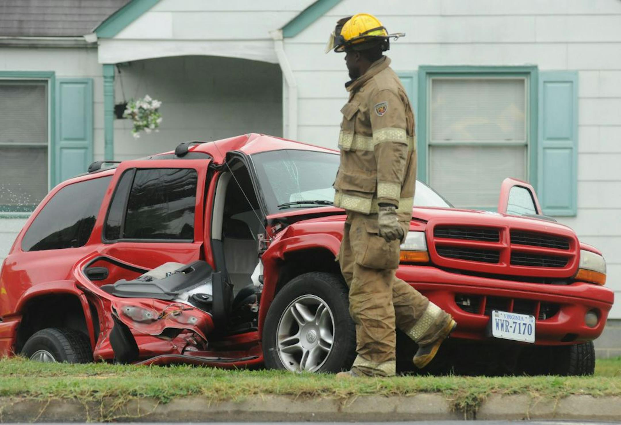 A fire fighter walks by a mangled Dodge SUV following a crash between a Petersburg City Public Schools bus Monday, Oct. 8, 2012 in Petersburg, Va. The driver of the SUV was charged and there were no children aboard the bus at the time.