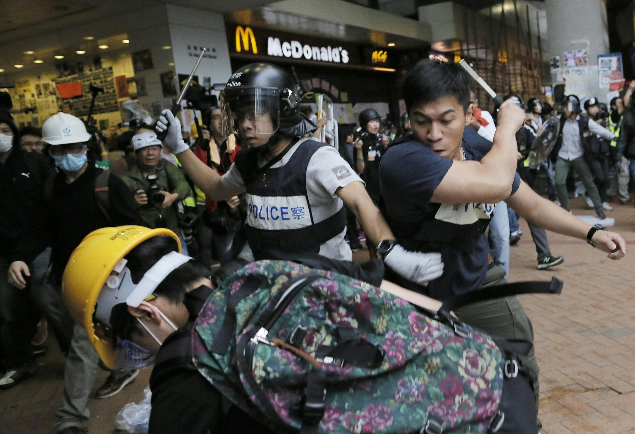 Police officers beat up protesters as they try to disperse them outside government headquarters in Hong Kong Monday, Dec. 1, 2014. Pro-democracy protesters clashed with police as they tried to surround Hong Kong government headquarters late Sunday, stepping up their movement for genuine democratic reforms after camping out on the city's streets for more than two months.