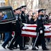 The Burnsville Police Honor Guard carried the casket of one of two fallen officers in front of family outside Ballad-Sunder Funeral and Cremation in J