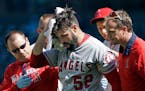 Los Angeles Angels starting pitcher Matt Shoemaker is assisted off the field after being hit by a line drive from Seattle Mariners' Kyle Seager in the