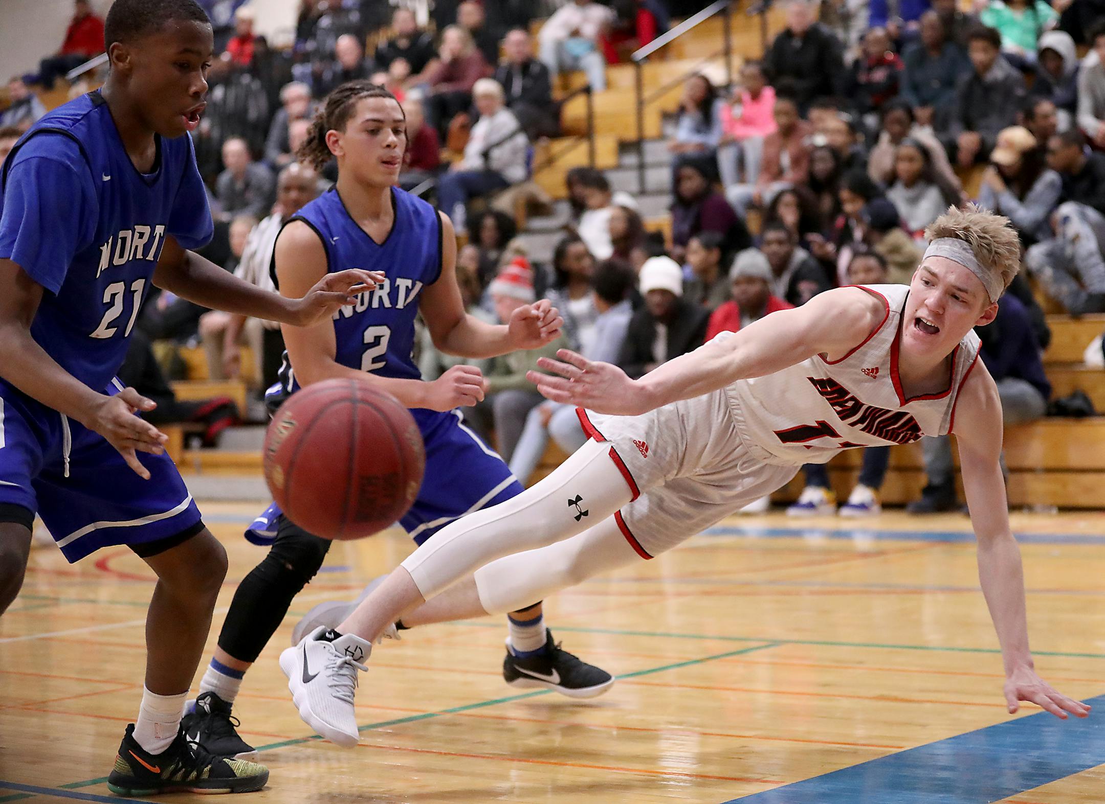 Drake Dobbs of Eden Prairie makes a diving pass as Trej Holloman (21) and Eli Campbell (2) of Minneapolis North defend.