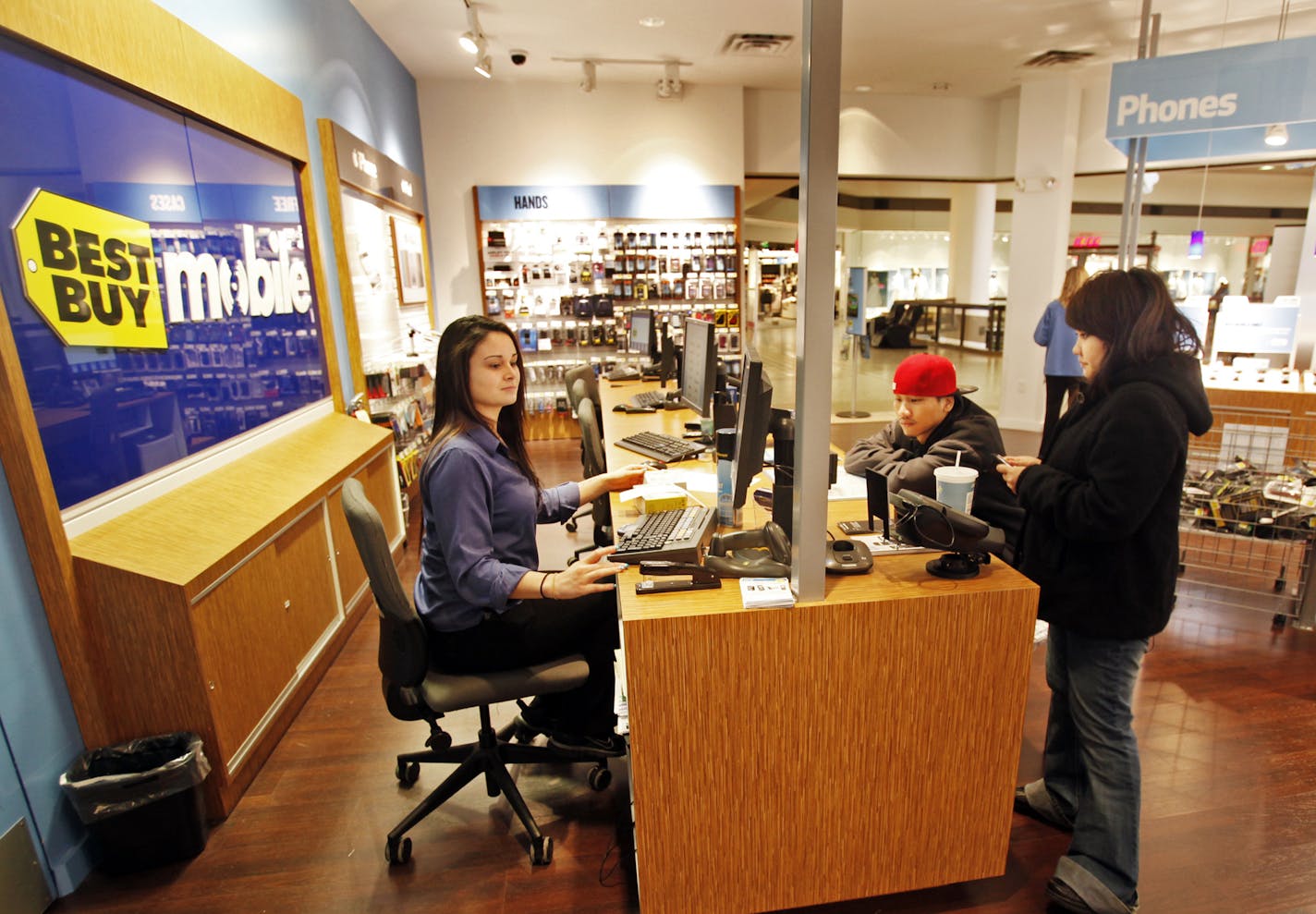 DAVID JOLES &#x201a;&#xc4;&#xa2; djoles@startribune.com -April 14, 2011- White Bear Lake, MN- : Best Buy has announced they plan to reduce their total retail stores space by 10%, which is a lot. Also, as they go forward, the smaller footprint BestBuy Mobile stores will be a focus of their growth. In this photo:] Best Buy sales lead Kelsee Grillo, helps customers Thao Xiong, center, and Amy Lee, right, of St. Paul, with an exchange on a cell phone at the Best Buy Mobile store in the Maplewood Mal