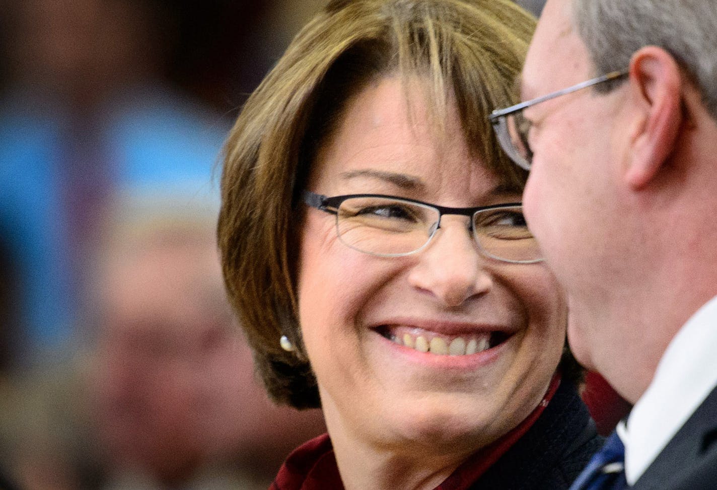 Senator Amy Klobuchar smiled at a veteran seated behind her at Hastings High School. ] GLEN STUBBE * gstubbe@startribune.com Tuesday, November 11, 2014 Hastings High School Veterans Day celebration. ORG XMIT: MIN1411121448041498