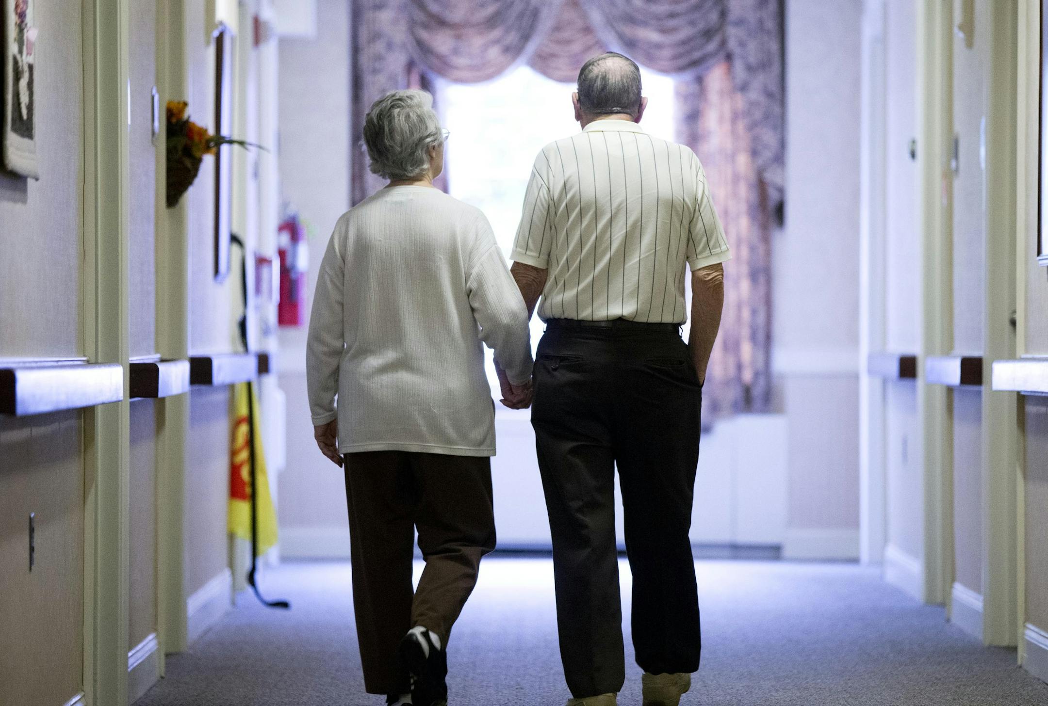Decima Assise, who has Alzheimer's disease, and Harry Lomping walk the halls, Friday, Nov. 6, 2015, at The Easton Home in Easton, Pa. Nursing homes and assisted living facilities are increasingly using sight, sound and other sensory cues to stimulate memory in people with Alzheimer's disease and other forms of dementia. (AP Photo/Matt Rourke) ORG XMIT: PAMR211