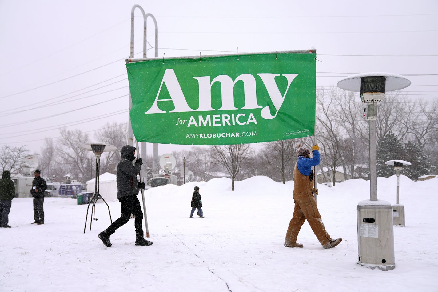 Volunteers Tim Schumann, left, and Chase Cushman moved an Amy for America sign into place Sunday morning ahead of Sen. Amy Klobuchar's announcement.