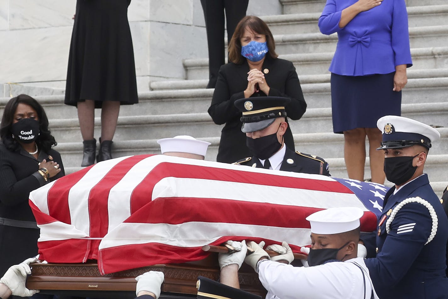 U.S. Congresswomen look on as the flag-draped casket of Justice Ruth Bader Ginsburg is carried out by a joint services military honor guard after lying in state at the U.S. Capitol, Friday, Sept. 25, 2020, in Washington. (Jonathan Ernst/Pool via AP)