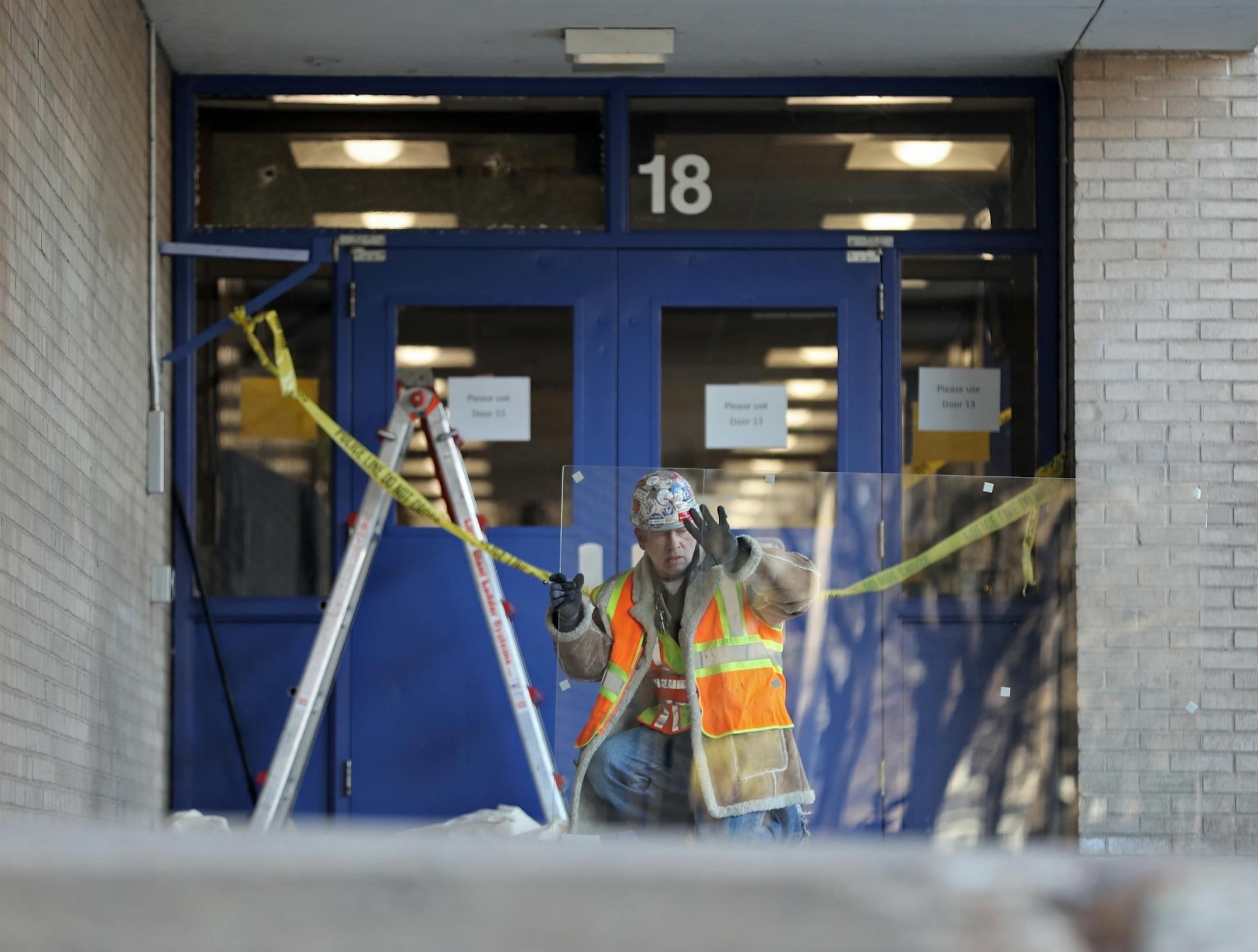 A man with Minneapolis Public Schools repaired the glass in an entryway at North High School after bullets struck while school was in session.