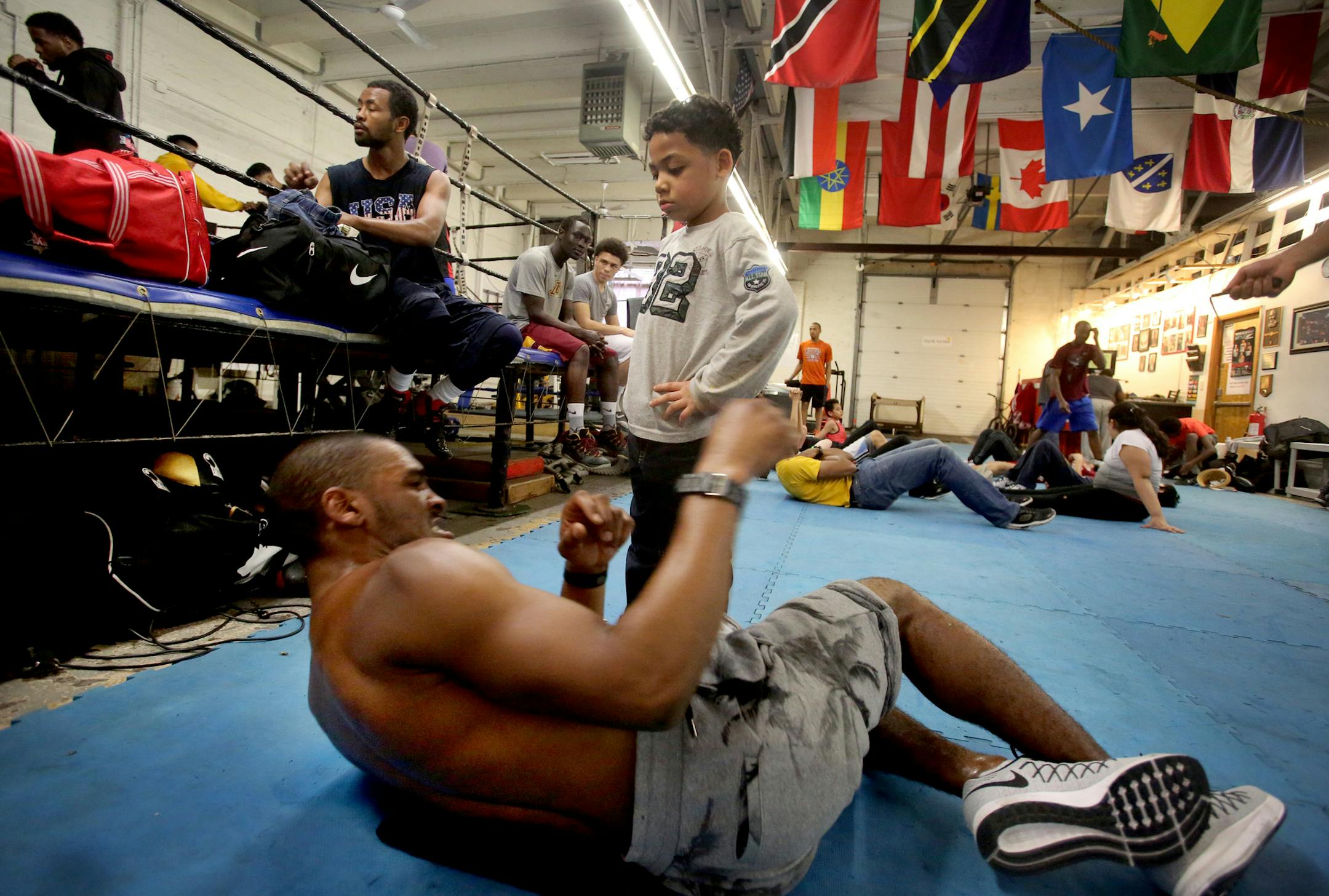 DeParis Frazier, 6, keeps an eye on boxer Dwight Lewis of S. St Paul as Lewis does abdominal work Monday, April 18, 2016, at Circle of Discipline in Minneapolis, MN.](DAVID JOLES/STARTRIBUNE)djoles@startribune Circle of Discipline is located in a historically tough neighborhood near the Midtown Global Market, off of Lake Street-- a melting pot where restaurant menus are more likely to be written in Spanish than English. It is the home gym of several pro fighters, including welterweight boxer Jam