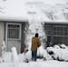 Early Monday Mike Anderson of Minneapolis raked his roof to clear snow from forming ice dams after a storm dumped nearly 16 inches of snow in the Twin