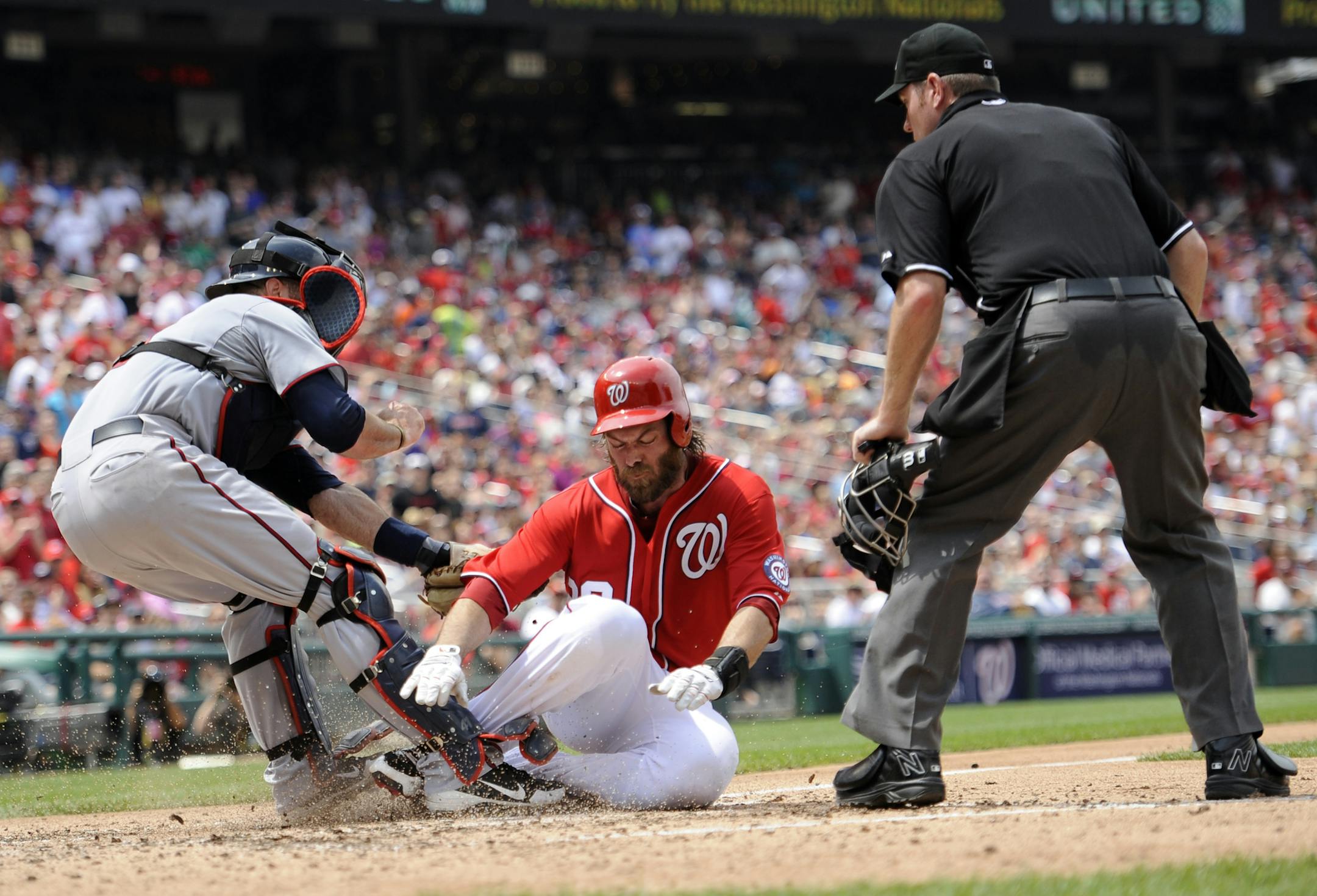 Washington Nationals' Jayson Werth, center, is out at the plate by Minnesota Twins catcher Ryan Doumit, left, during the fourth inning of the first baseball game of a day-night interleague doubleheader, Sunday, June 9, 2013, in Washington. Also seen is home plate umpire Chris Conroy at right. (AP Photo/Nick Wass)