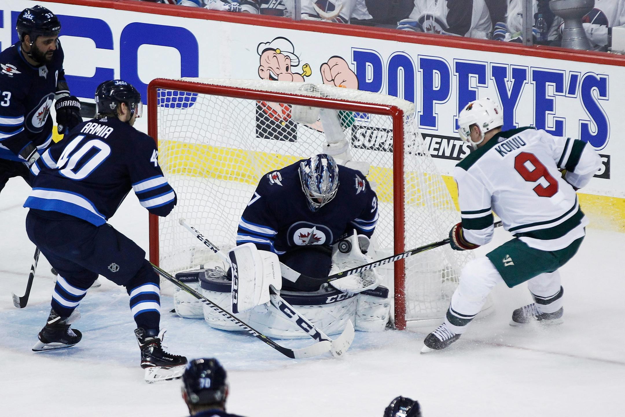 Winnipeg Jets goaltender Connor Hellebuyck (37) makes a save on a shot from Minnesota Wild's Mikko Koivu (9) as Jets' Joel Armia (40) defends during the third period of Game 1 in an NHL hockey first-round playoff series Wednesday, April 11, 2018, in Winnipeg, Manitoba.