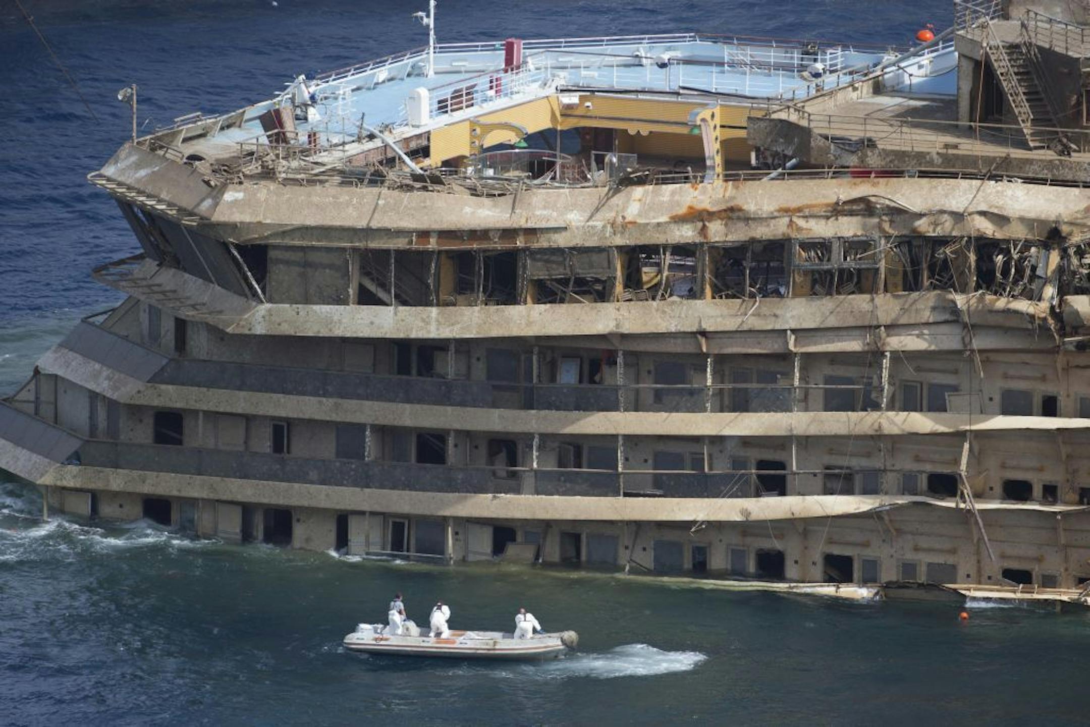 Workers on a boat sail past the Costa Concordia ship after it was lifted upright, on the Tuscan Island of Giglio, Italy, Tuesday, Sept. 17, 2013.