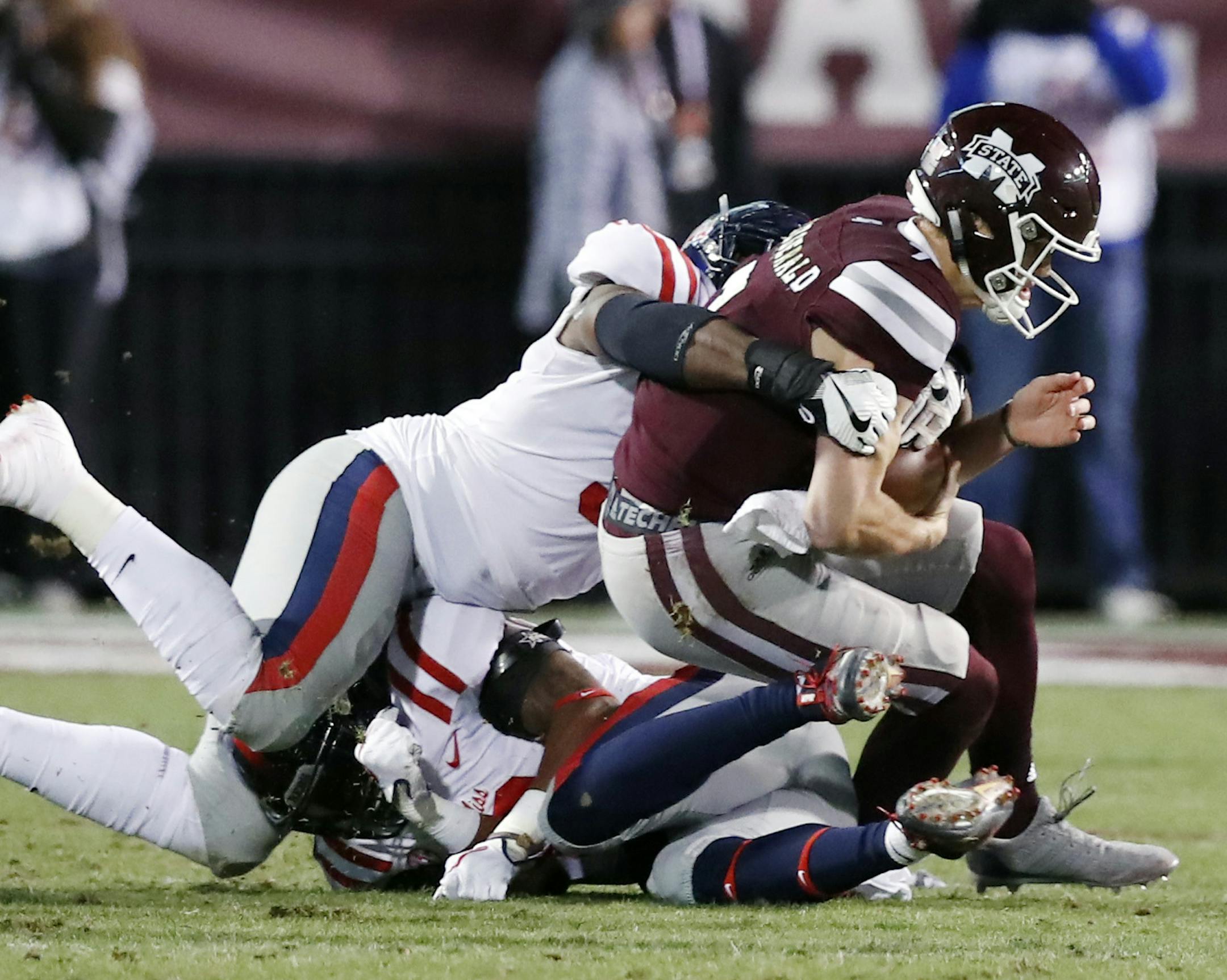 Mississippi State quarterback Nick Fitzgerald, right, is tackled by Mississippi defenders and is injured during the first half of an NCAA college football game in Starkville, Miss., Thursday, Nov. 23, 2017. Fitzgerald left the field on a cart. (AP Photo/Rogelio V. Solis)