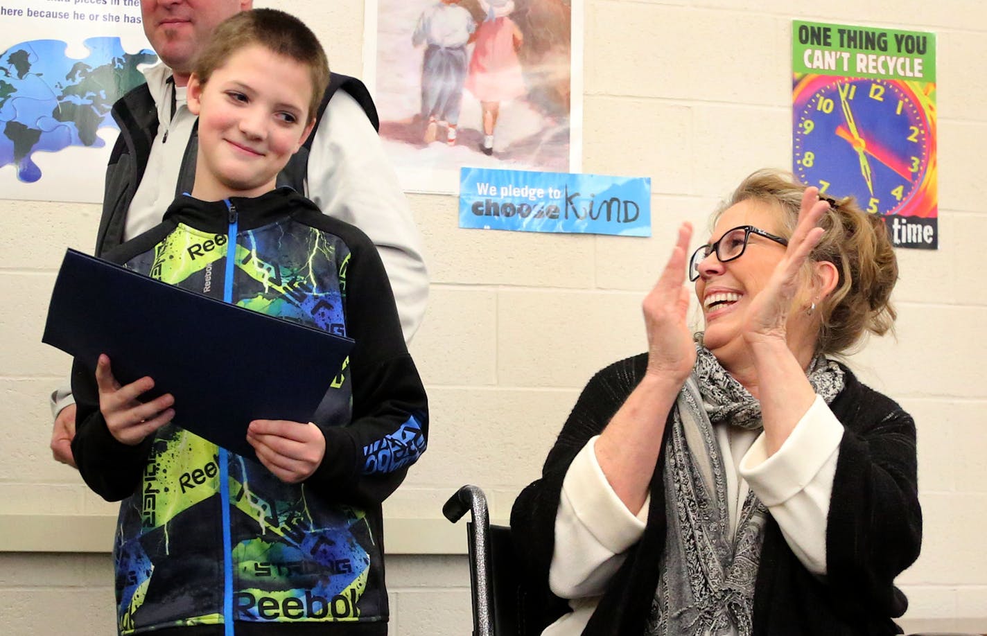 Fridley Middle School and Fridley Police Department recognized sixth grader Colby Hansen for his role in assisting injured homeowner Laurie Harms, who credits the boy with saving her life after she recently slipped and fell and shattered her hip and played for a few hours in the cold waiting for help before Hansen came to the rescue and called 911 and got medical assistance for Harms. Here, Hansen holds one of the awards as Harms applauds him Tuesday, Feb. 14, 2017, at Fridley Middle School in F