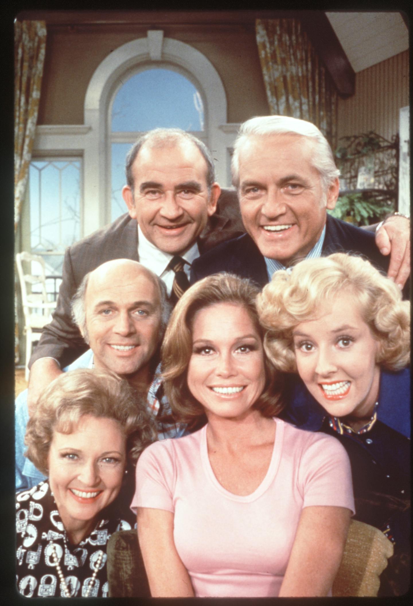 The Mary Tyler Moore Show (television). Mary Tyler Moore is front and center. Ed Asner and Ted Knight are left to right in back. Georgia Engel is at right. Gavin MacLeod is at left in front of Asner. Betty White is at lower left. File photo courtesy of CBS Television.