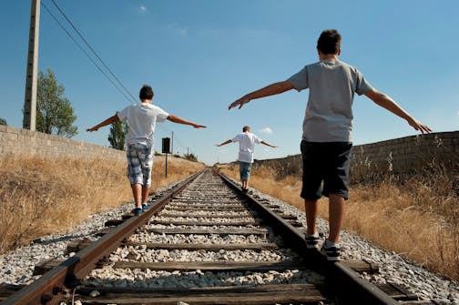 Three teenagers walking along a railroad