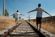 Three teenagers walking along a railroad