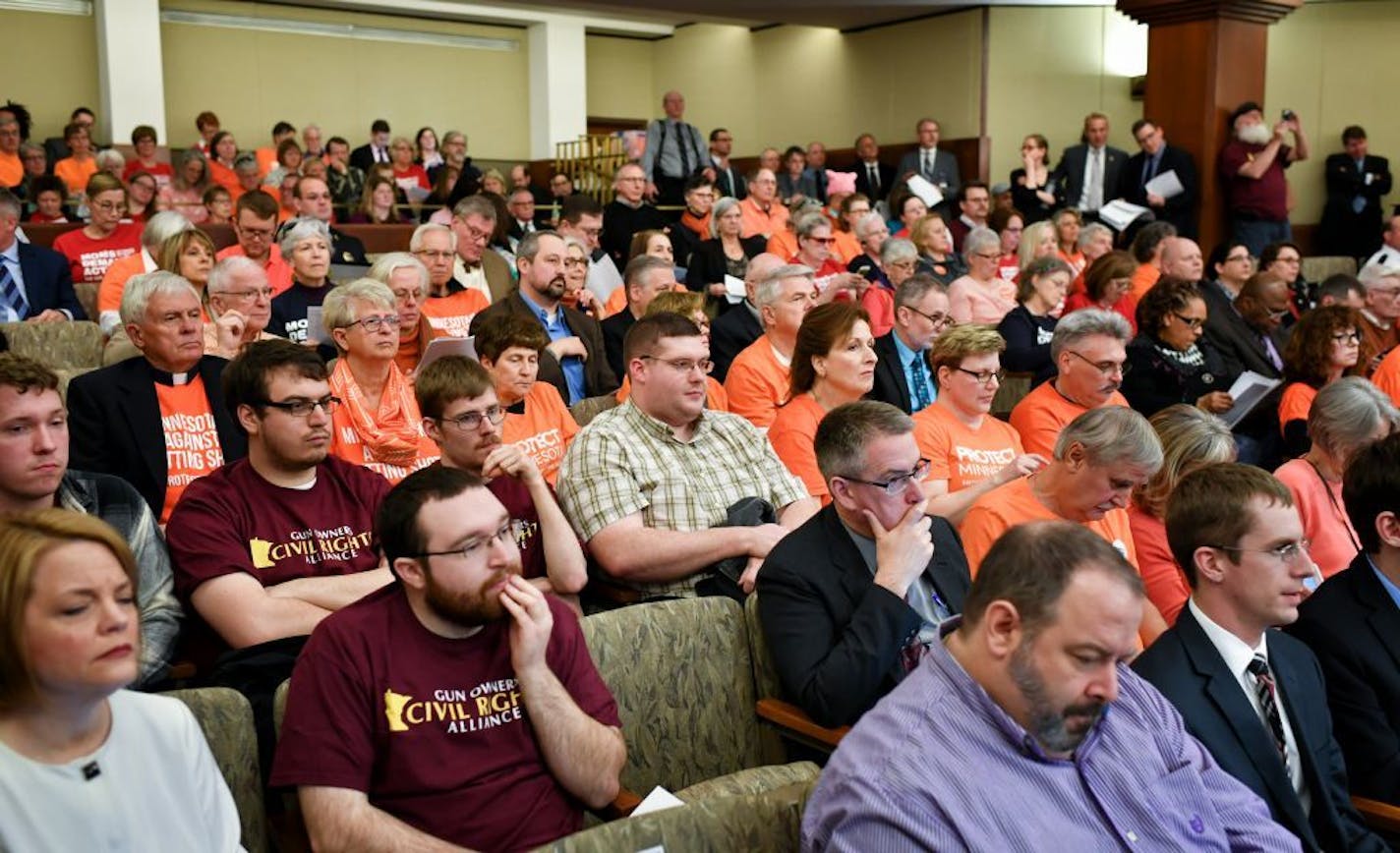 Members of the gun owners civil rights alliance wearing maroon and members of a coalition of people against expanded gun rights, mostly wearing orange and red, sat in the Capitol during the gun hearing.