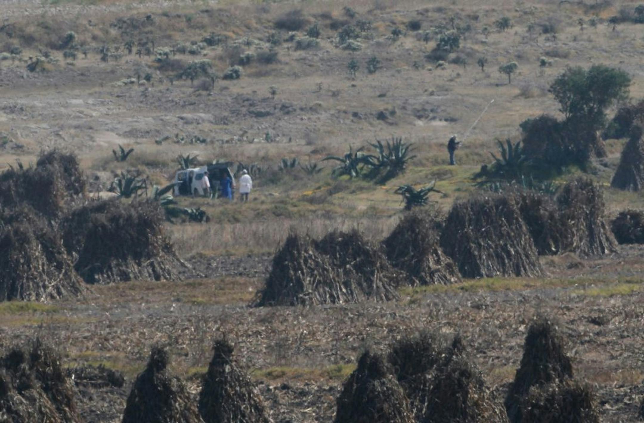 Men stand next to an unidentified vehicle inside a cordoned off area in a field near the village of Hueypoxtla, Mexico, Thursday, Dec. 5, 2013. National nuclear safety officials were engaged Thursday in the delicate task of recovering a stolen shipment of highly radioactive cobalt-60 presumed to be found in this rural field.