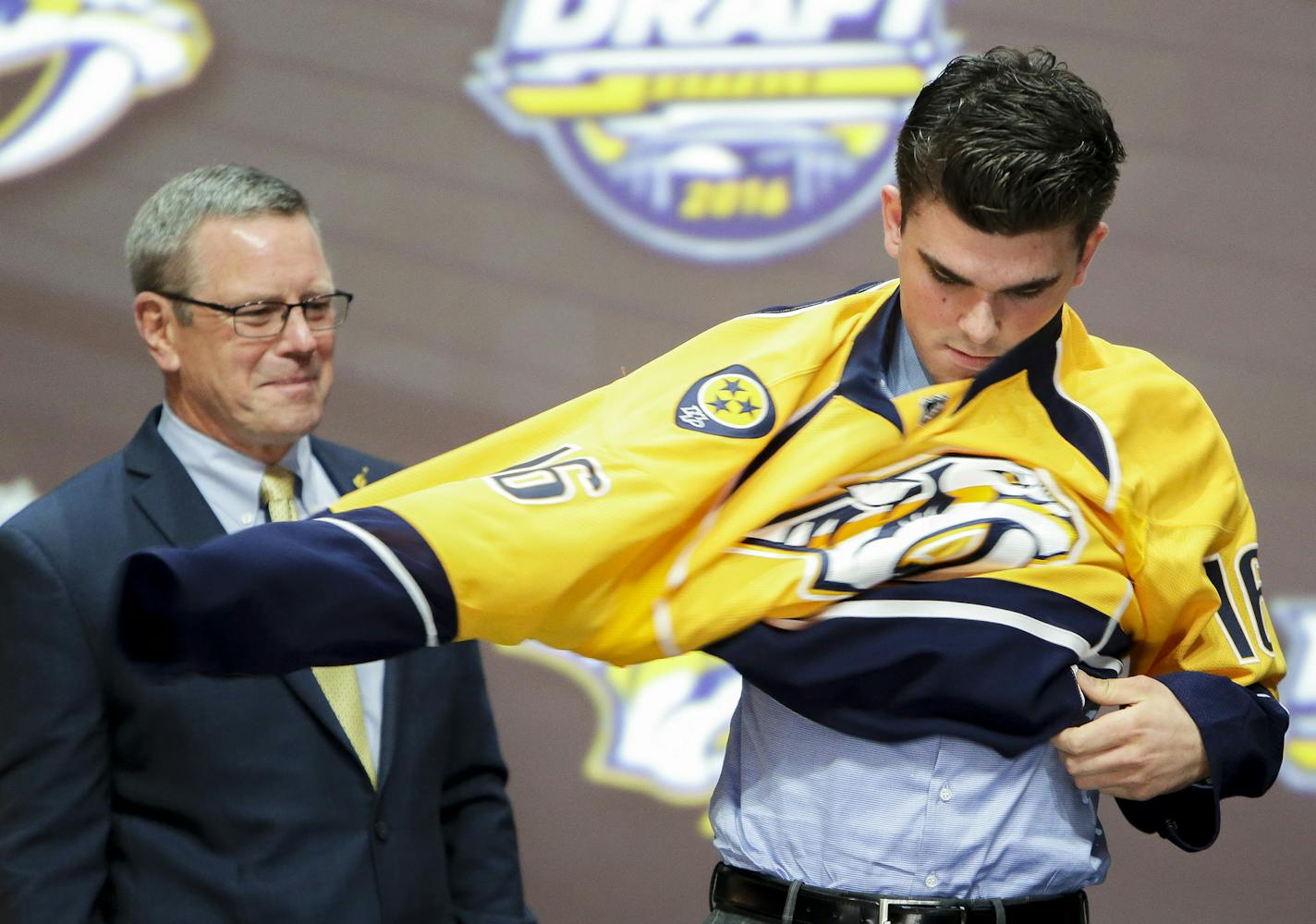 June 24, 2016: Dante Fabbro dons the Predators jersey after he was selected as the 17th pick in the first round of the 2016 NHL Entry Draft at First Niagara Center in Buffalo, NY. at left is Predators assistant general manager Paul Fenton. (Photo by John Crouch/Icon Sportswire.) (Icon Sportswire via AP Images) ORG XMIT: 263699