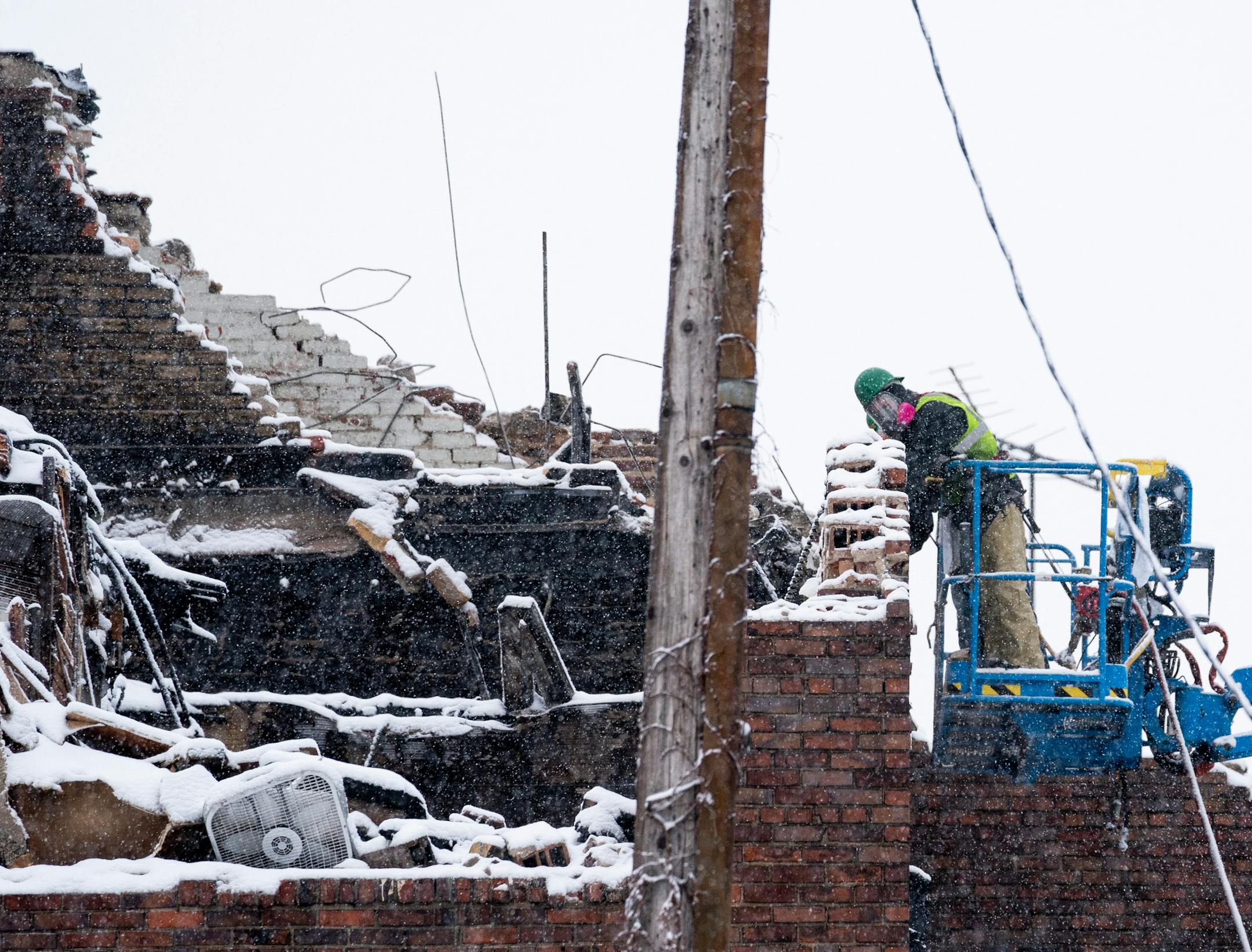 Crews worked though heavy snow, slowly knocking down walls abutting a neighboring garage that was undamaged by the fire. ] MARK VANCLEAVE ¥ Workers ripped down walls of the burned Francis Drake Hotel on Monday, Dec. 30, 2019 in Minneapolis.