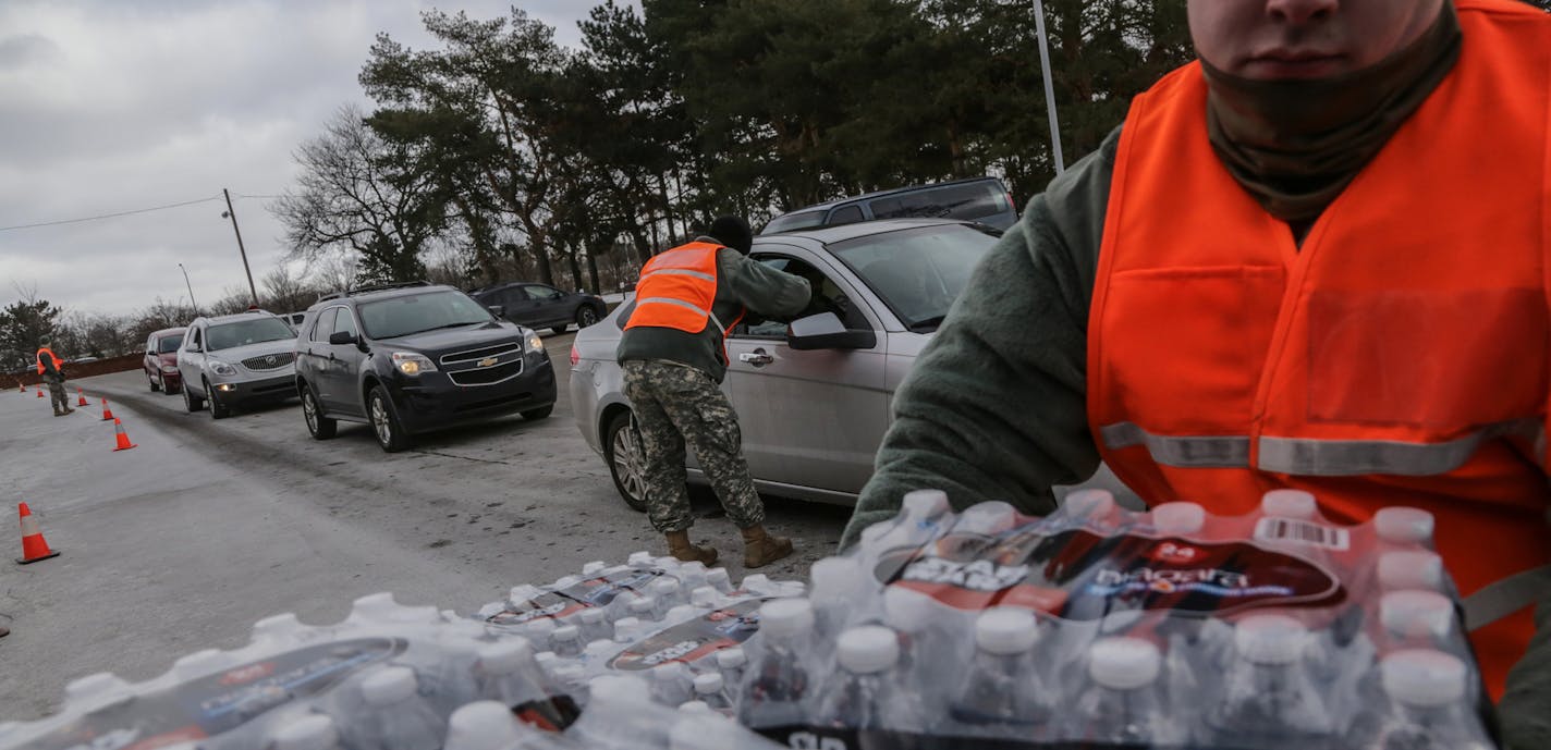 In this photo taken Monday, Jan. 18, 2016, U.S. Army National Guard 125th Infantry Battalion members from Michigan hand out water at Flint Fire Department Station No. 1 to help residents dealing with lead in their drinking water in Flint, Mich. Gov. Rick Snyder is the target of two class-action lawsuits filed by Flint residents over the state's handling of the city's water crisis, The Flint Journal reported. (Ryan Garza/Detroit Free Press via AP) DETROIT NEWS OUT; TV OUT; MAGS OUT; NO SALES; MAN