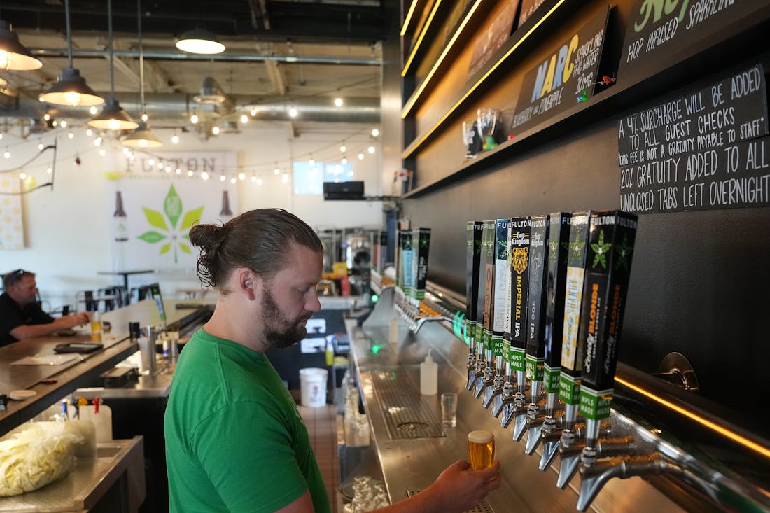 Bartender Connor Gomer pours beer at the Fulton Beer Taproom on Tuesday. This fall the taps will also carry Finnegans beer; the breweries are forming 