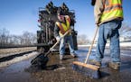 Street service workers Lance Hamby, left, and Bradley Therres filled potholes on Shepard Road on March 15. A new report says St. Paul needs to spend a