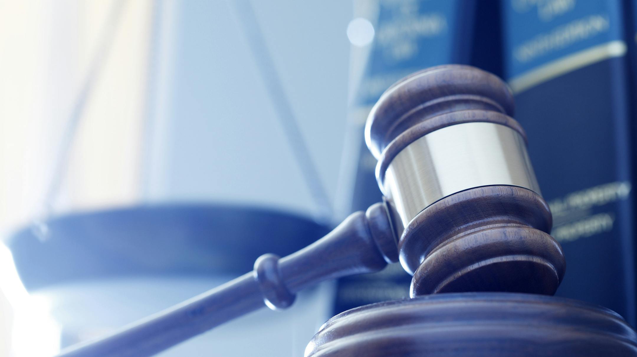 iStock
A gavel rests on its sounding block with a several law books and a justice scale out of focus in the background.