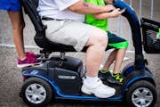 Gary Koch, center, of Wausau, Wis., gave his grandchildren Addison Koch, left, 7, and Grayson Koch, 6, a quick ride on his motorized scooter in the Mi