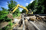 MNDOT crews clear a mudslide and place huge rocks around a washed out culvert along Highway 66, June 18, 2014 in Mankato.