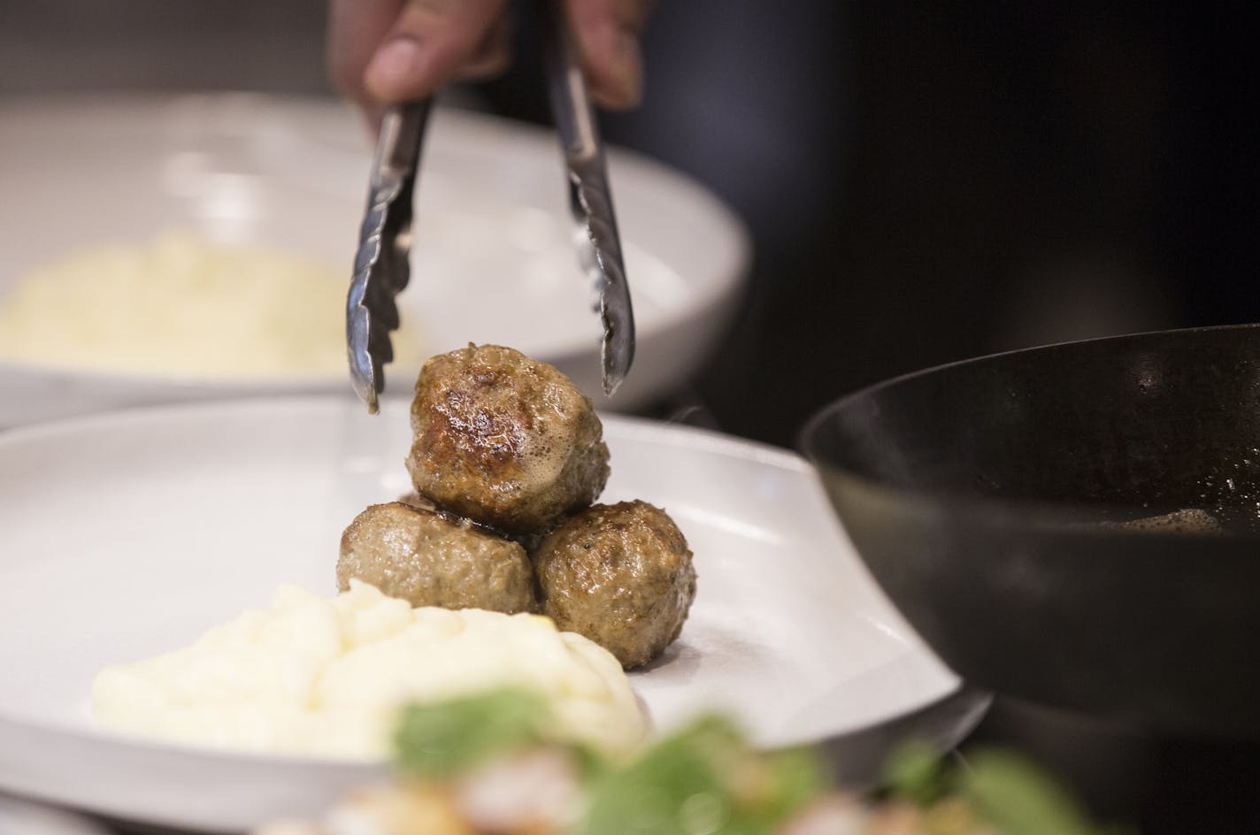 Swedish meatballs being plated in the kitchen.