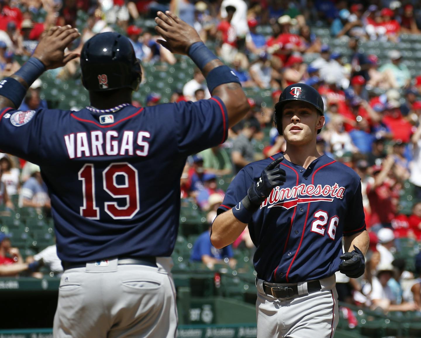 Minnesota Twins' Max Kepler (26) celebrates his grand slam home run as he arrives home with Kennys Vargas against the Texas Rangers during the fifth inning of a baseball game, Sunday, July 10, 2016, in Arlington, Texas. (AP Photo/Jim Cowsert)