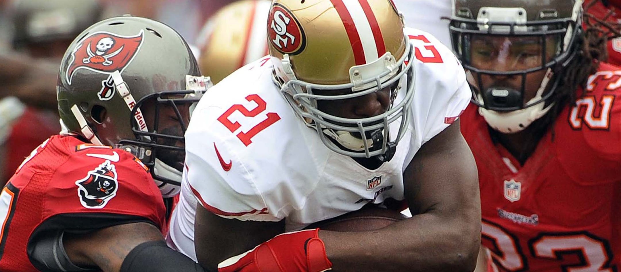 San Francisco 49ers running back Frank Gore (21) slips between Tampa Bay Buccaneers cornerback Darrelle Revis (24) and strong safety Mark Barron (23) during the first quarter of an NFL football game Sunday, Dec. 15, 2013, in Tampa, Fla. The 49ers won the game 33-14. (AP Photo/Brian Blanco)