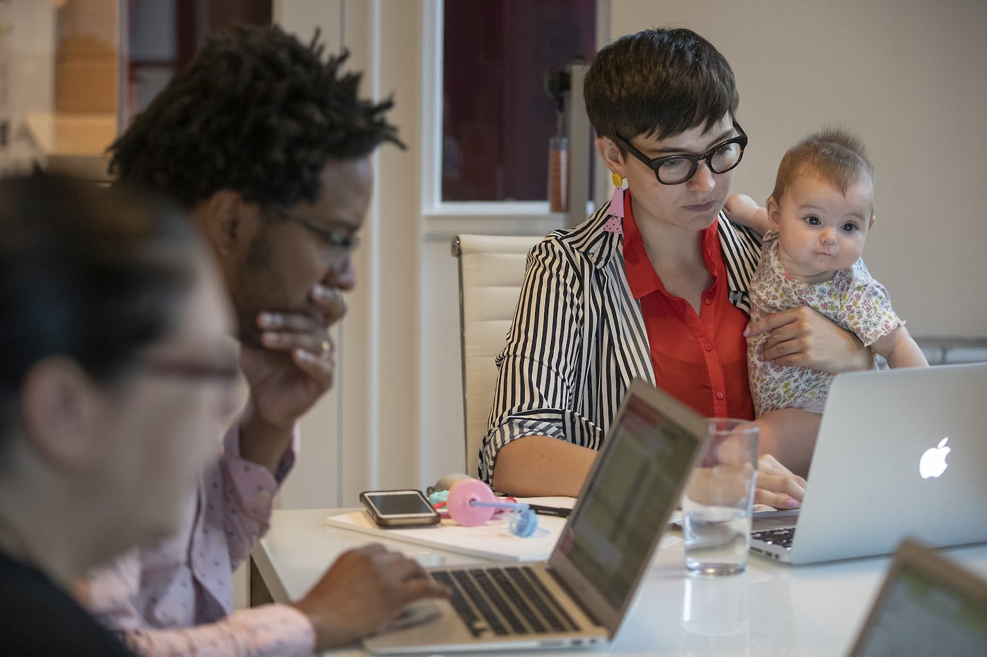 Baby Dani sat patiently with her mother, Jamie Millard, executive director of Pollen, at a meeting with Julie Cohen, left, and Jerome Rankine in June in Minneapolis.