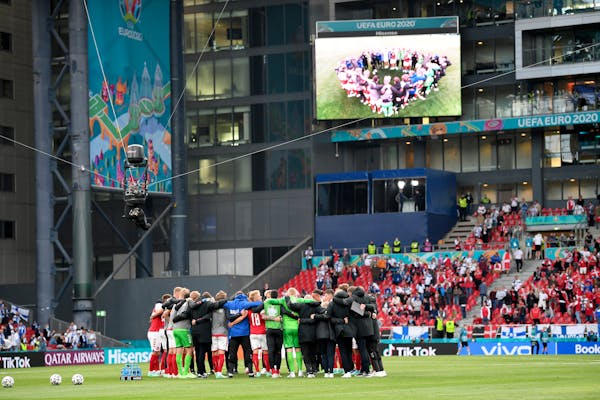 Denmark players gather together on the pitch as they return to resume the match after Christian Eriksen collapsed and had to be taken to the hospital