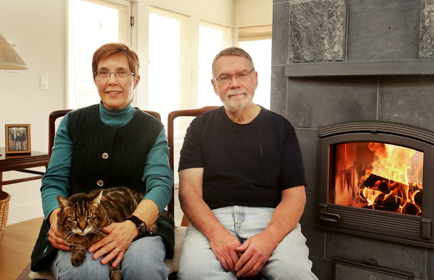 Susan and Jeff Saffle's passion for birdwatching and nature drove the design of this Scandinavian version of a Prairie Modern home in Lake Elmo by Rehkamp Larson Architects. Here, Jeff and Susan Saffle sit with their cat Frank, next to their Finnish Tulikivi stove and fireplace which utilizes soapstone to retain radiant heat from the fire to produce comfort, warmth and efficiency Wednesday, Jan. 13, 2016, in Lake Elmo, MN.](DAVID JOLES/STARTRIBUNE)djoles@startribune.com Susan and Jeffrey Saffle