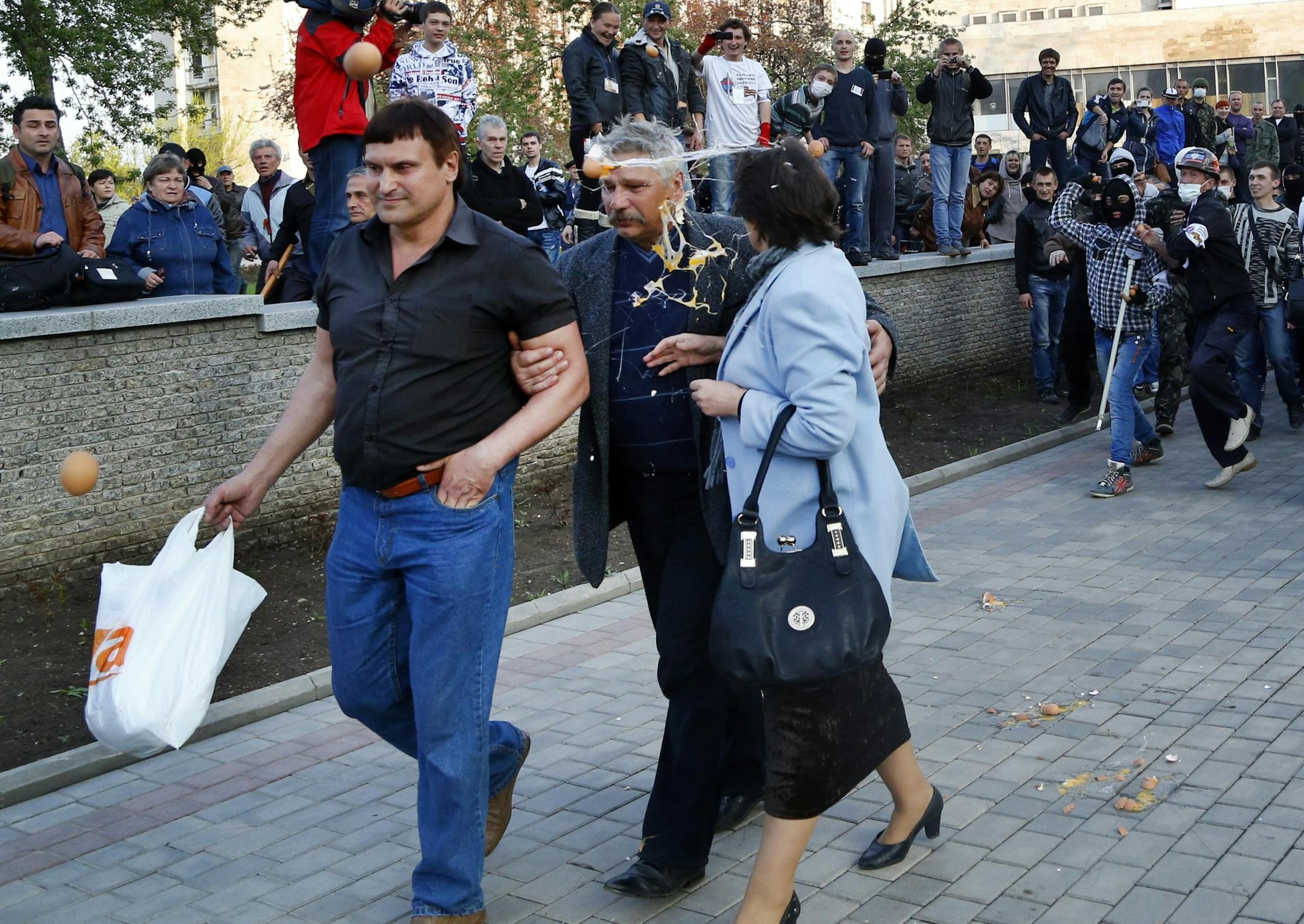 Pro Russia protestors, right, throw eggs at pro Ukrainian activists in Donetsk, eastern Ukraine, Tuesday, April 22, 2014. U.S. Vice President Joe Biden warned Russia on Tuesday that "it's time to stop talking and start acting" to reduce tension in Ukraine, offering a show of support for the besieged nation as an international agreement aimed at stemming its ongoing crisis appeared in doubt. (AP Photo/Sergei Grits)